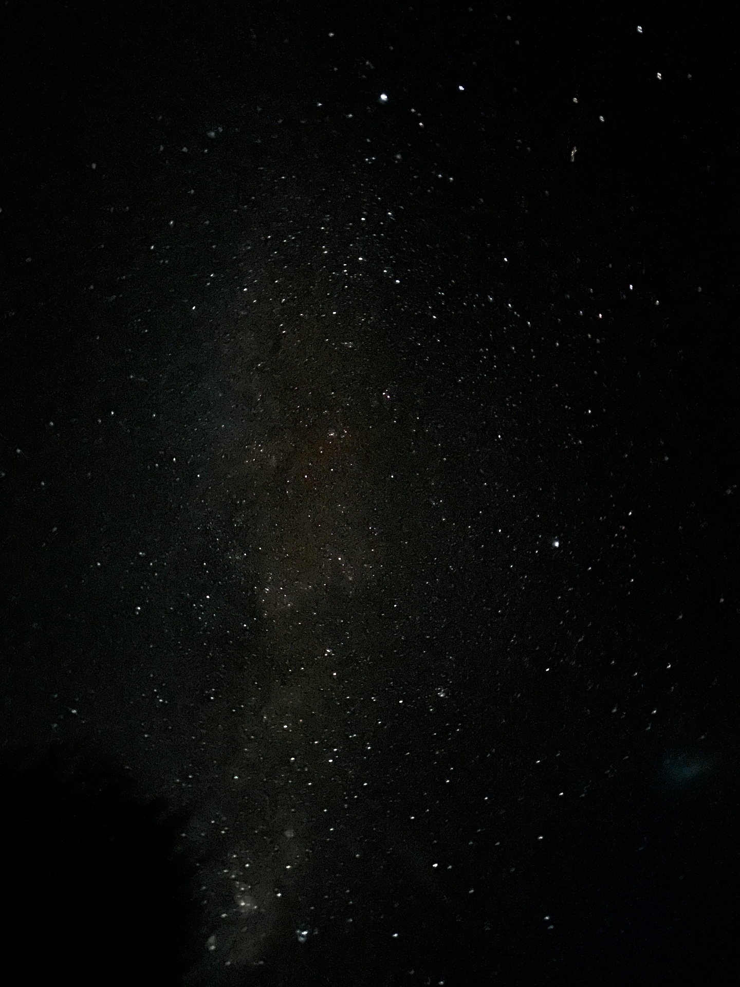 A long exposure of the Milky Way as a soft pink-grey band cutting vertically through a star-strewn sky.