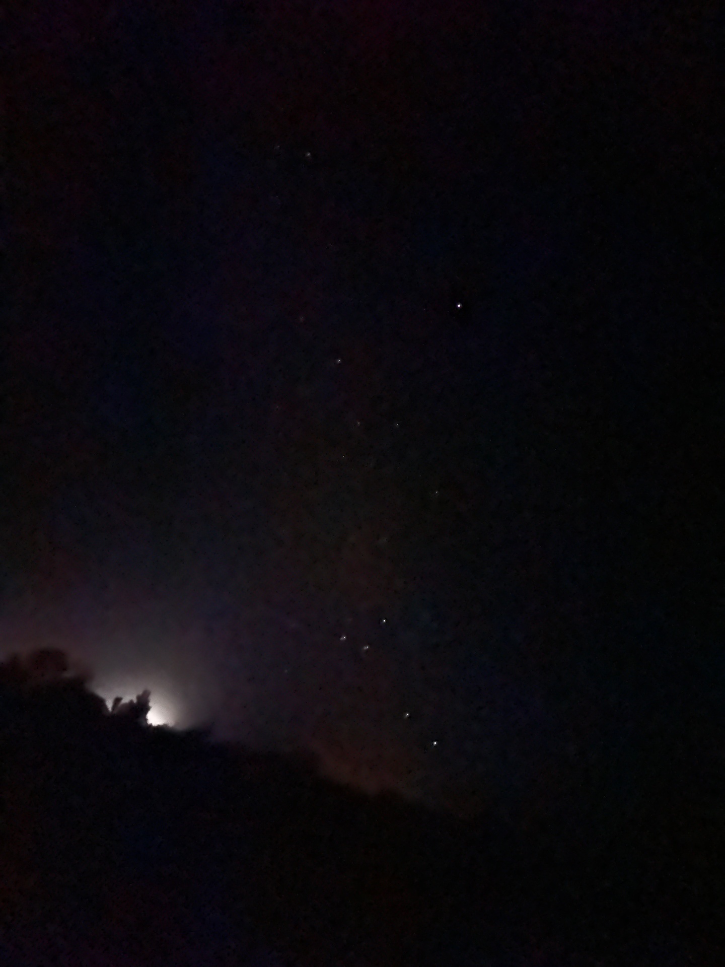 An almost-empty dark sky with a single bright star high in the frame and a soft cloud of distant light at the bottom-left edge.